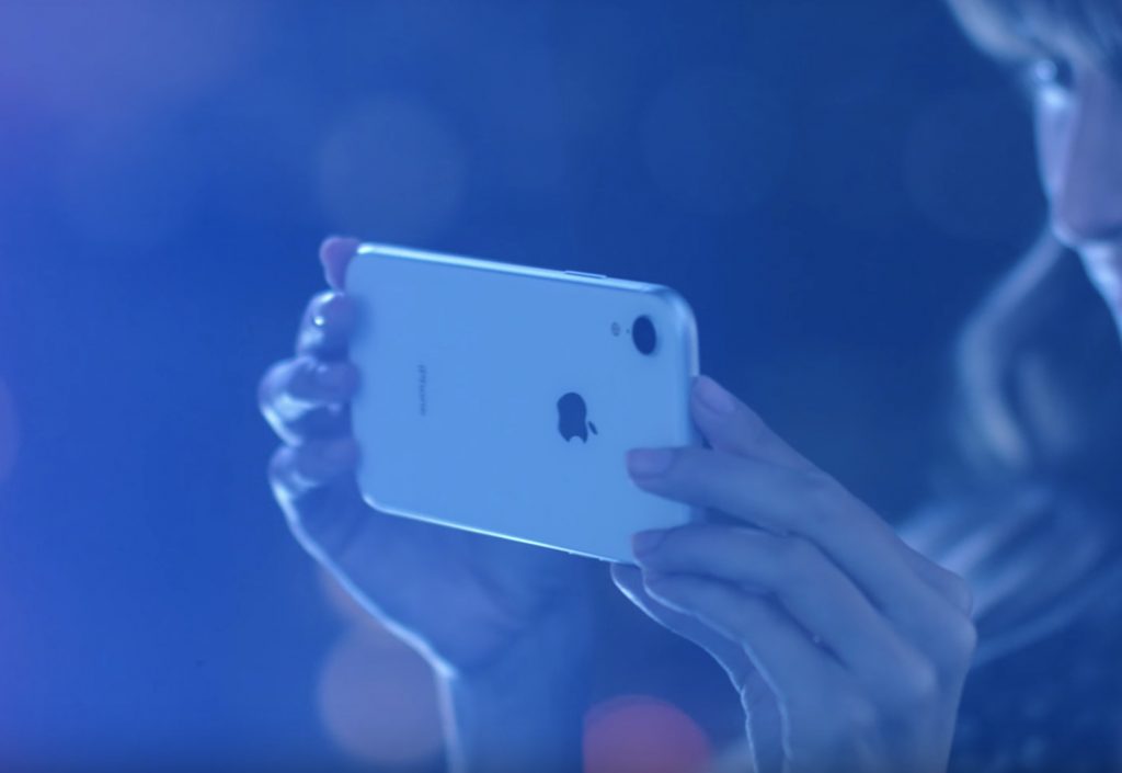 Picture of a woman holding an iPhone XR in white. 